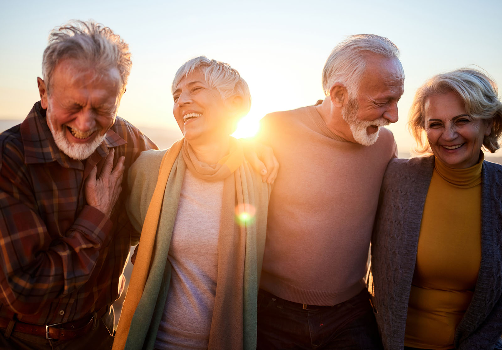 Des couples de seniors heureux communiquent en marchant en automne au coucher du soleil.