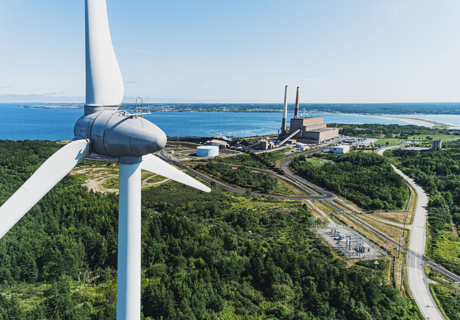 Vue aérienne par drone d'une éolienne au premier plan d'une centrale électrique au charbon.