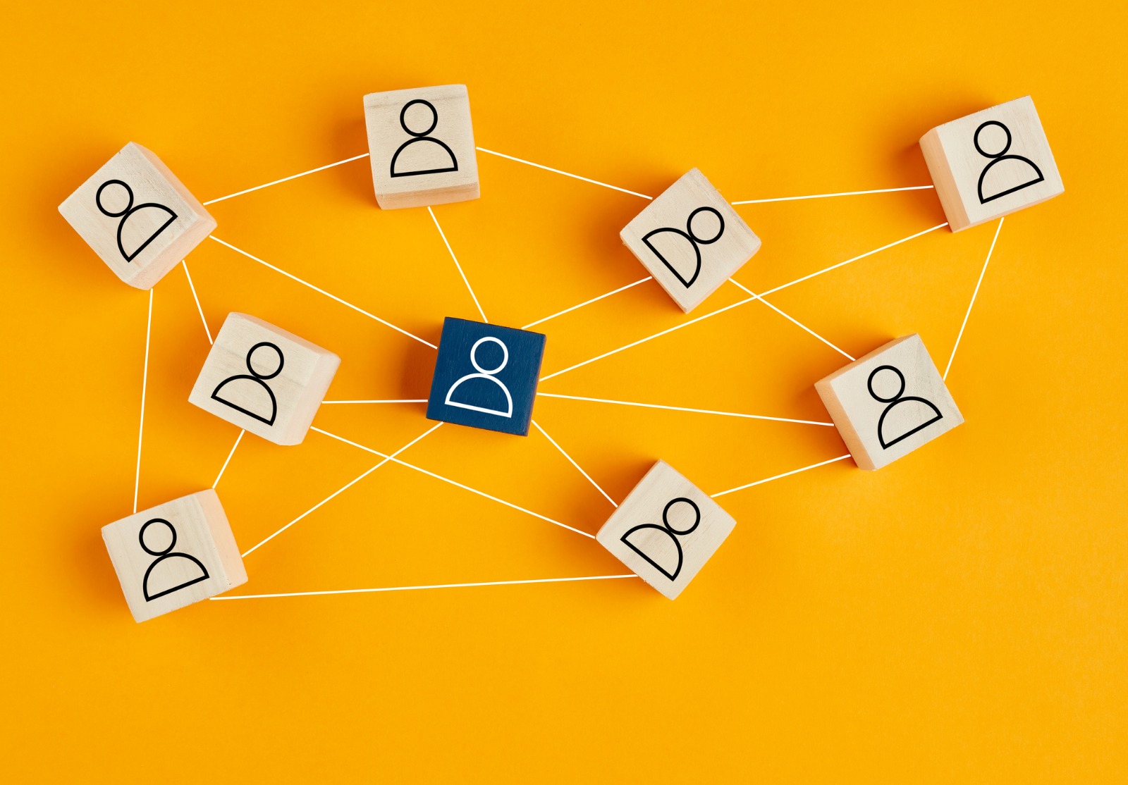 Blocs en bois avec l’icône de personnes sur le fond jaune. Structure organisationnelle, réseau social, leadership, team building, recrutement, management ou ressources humaines.
