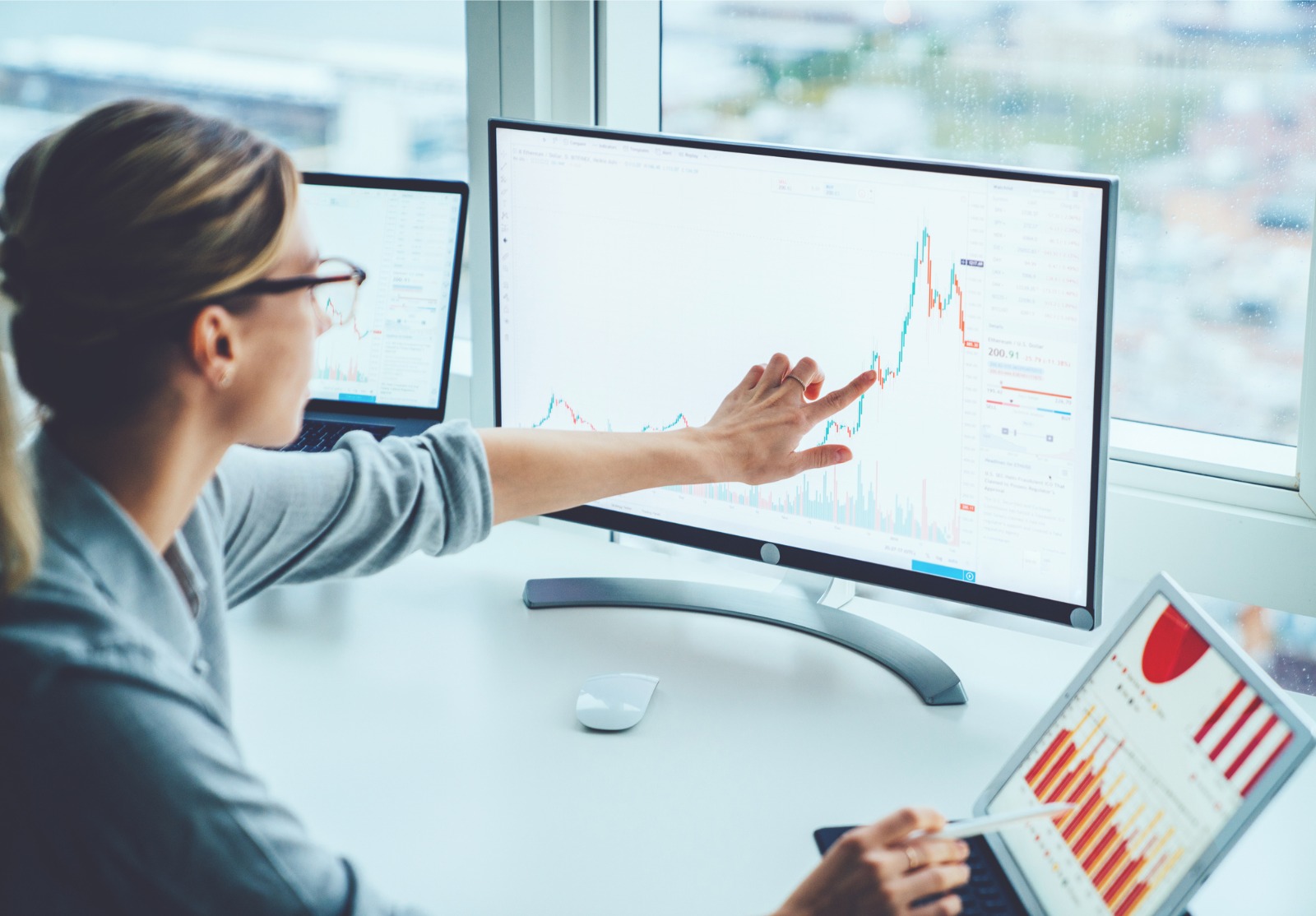 Une femme d'affaires étudie les marchés financiers pour calculer les risques et les bénéfices possibles. L'argent de comptabilité d'économiste féminin avec des graphiques de statistiques pointant sur l'écran de l'ordinateur au bureau.