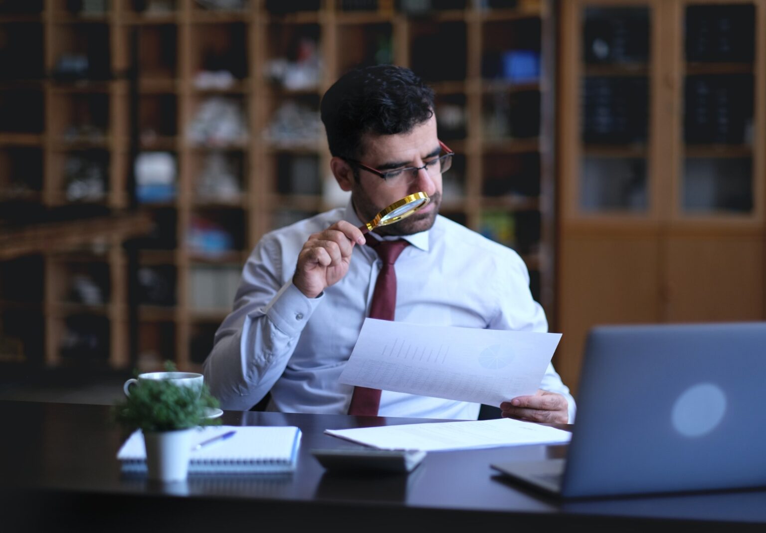 Un homme d’affaires examine les valeurs statistiques à la loupe.