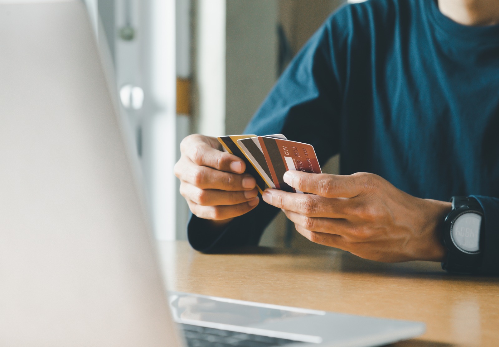 Homme tenant la main de la carte de crédit et utilisant un ordinateur portable à la maison, homme d’affaires ou entrepreneur travaillant, achats en ligne, commerce électronique, services bancaires en ligne, concept d’argent de poche.