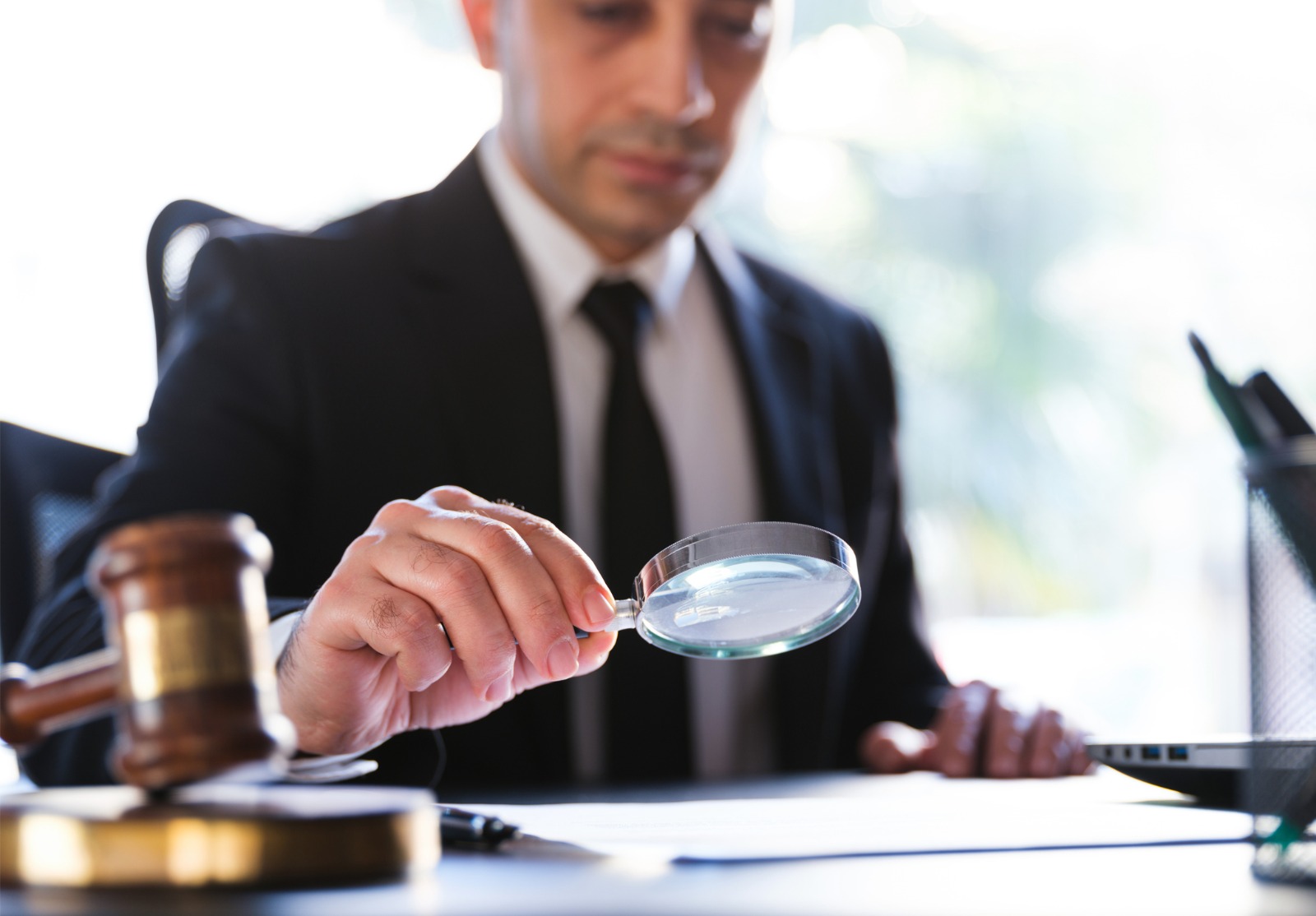 Homme dans le procès noir affichant un document légal utilisant soigneusement la loupe.