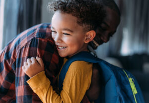 Adulte et petit enfant avec un sac à dos, s'embrassant et se souriant