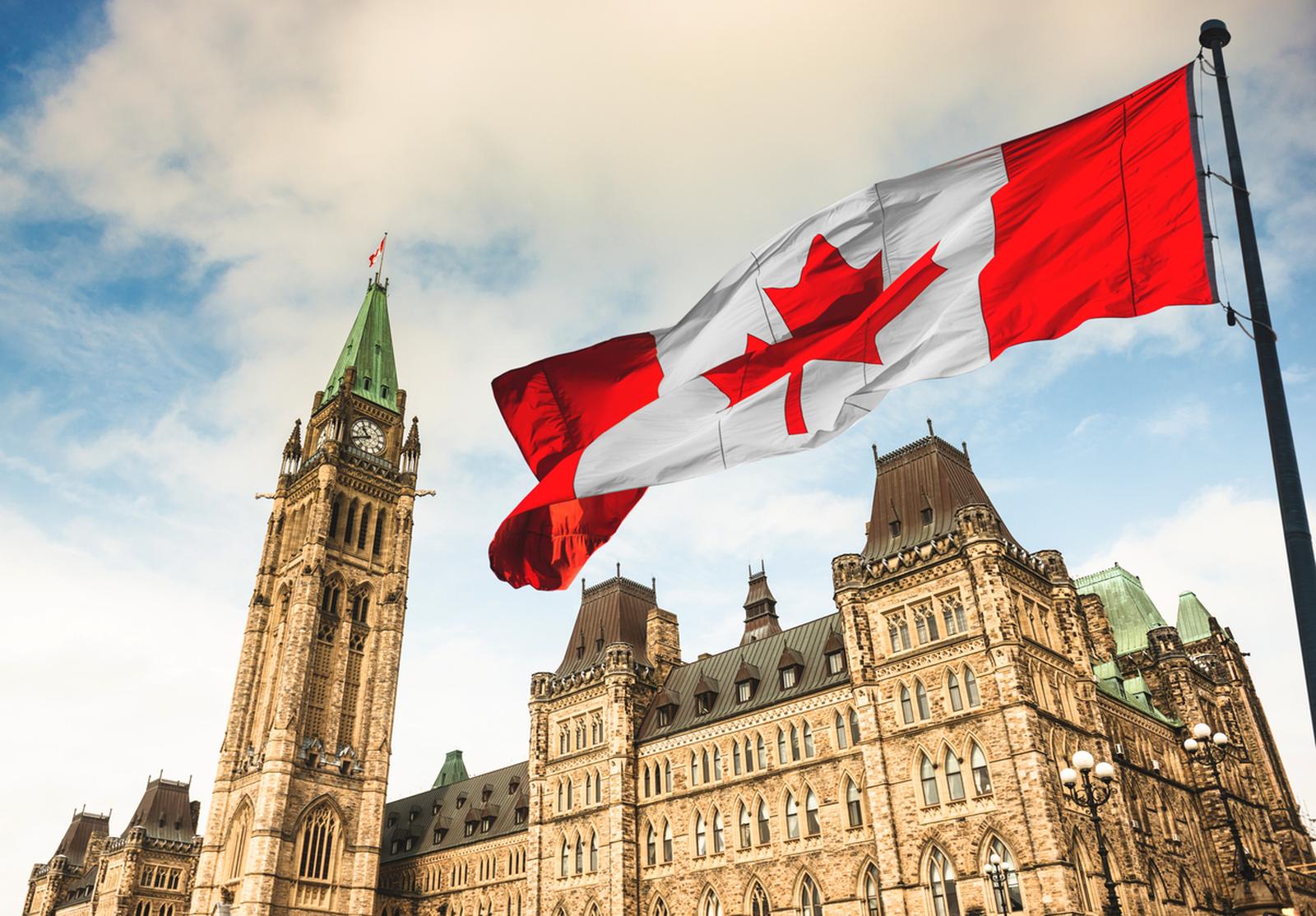Drapeau canadien flottant au vent devant la Tour de la Paix du Parlement canadien. Symbole fort du pays et de sa gouvernance.