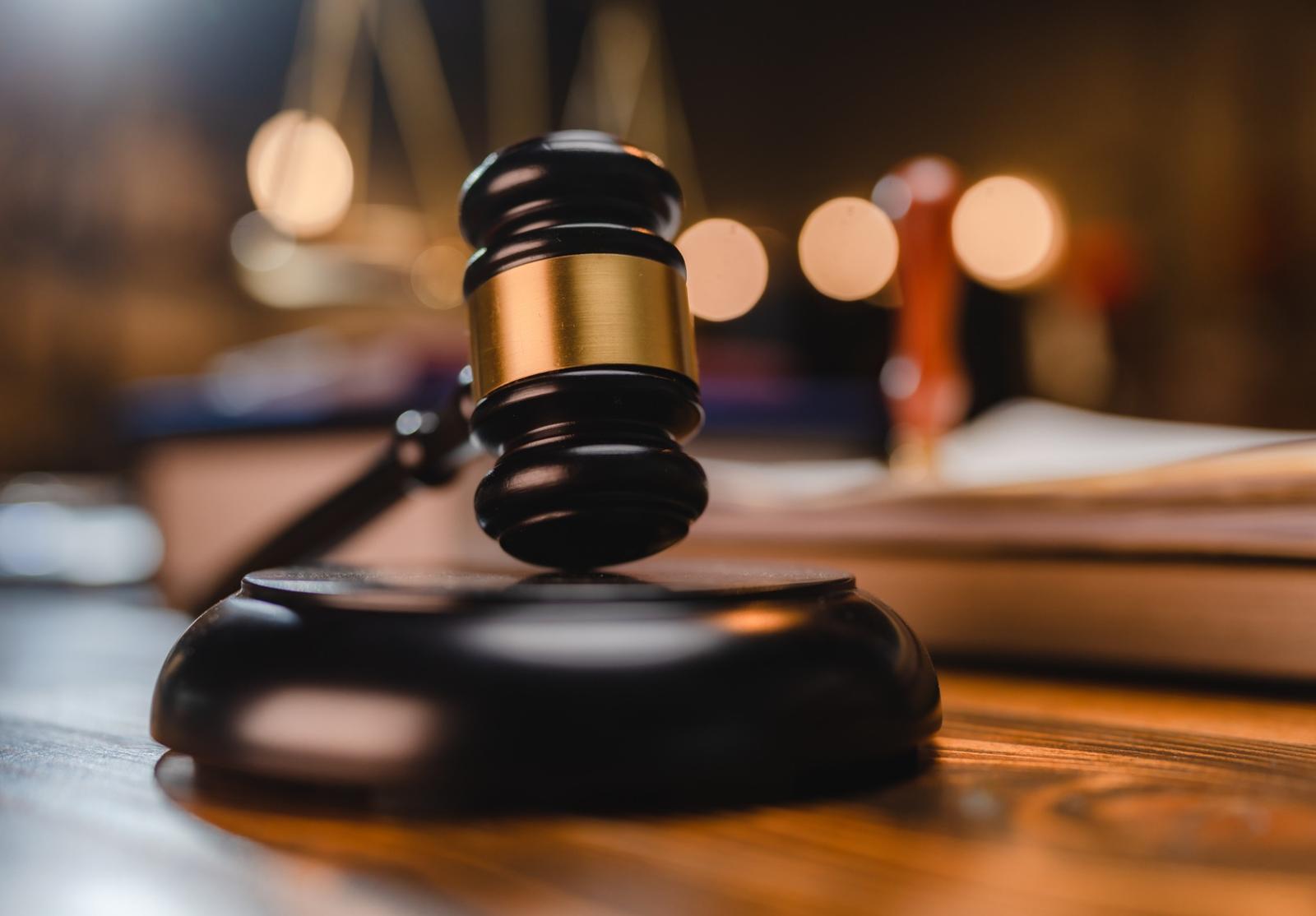 Marteau de juge en bois avec bague dorée, posé sur son socle, symbolisant la justice.