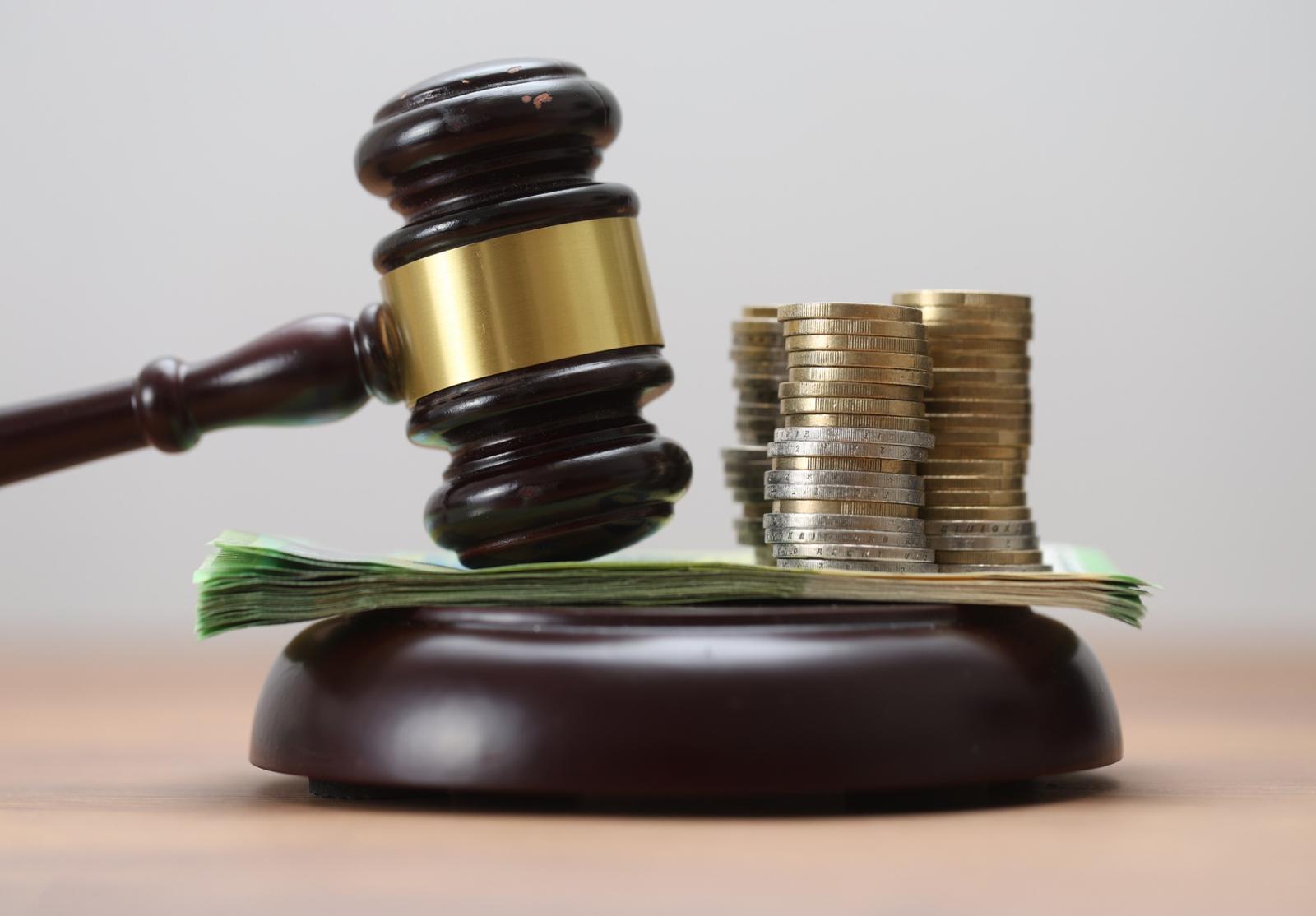 Marteau de juge doré posé sur une multitude de billets de 100 dollars américains.