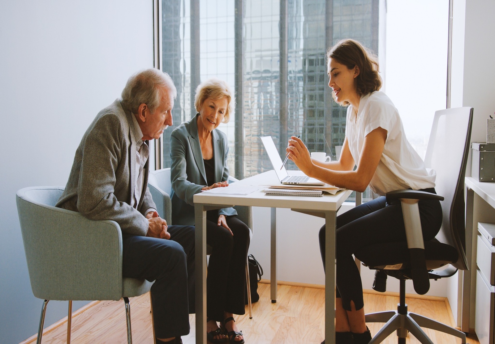 Conseillère discutant avec un couple de personnes âgées, représentant la gestion patrimoniale et le conseil personnalisé.